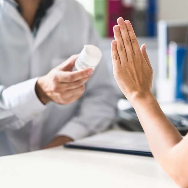 Pharmacist offering medication, person gesturing