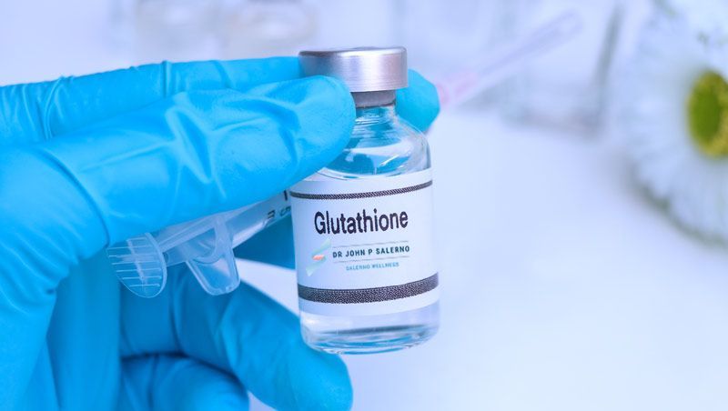 A gloved hand holds a vial labeled