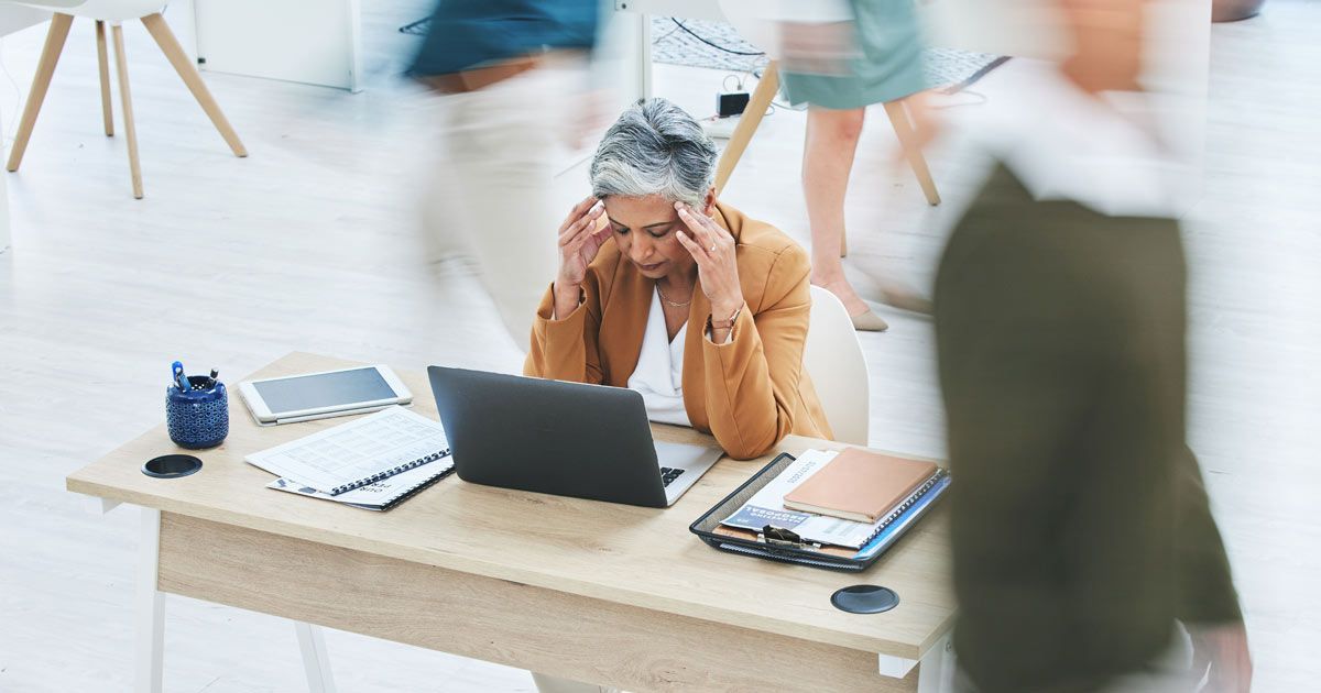 Many patients describe an inability to concentrate, forgetfulness, or mental sluggishness, making day-to-day productivity challenging. A woman with brain fog is sitting at a desk in front of a laptop computer, needing Hashimotos Thyroiditis Treatments NYC by Dr. John Salerno.
