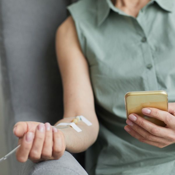 A woman is holding a cell phone while receiving Detox from Heavy Metal Poisoning with Advanced Medical Treatments at Salerno Wellness in Manhattan, NY and Connecticut.