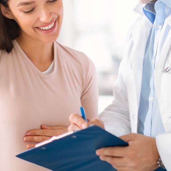 Pregnant woman smiling as doctor reviews her tests in a patient consultation