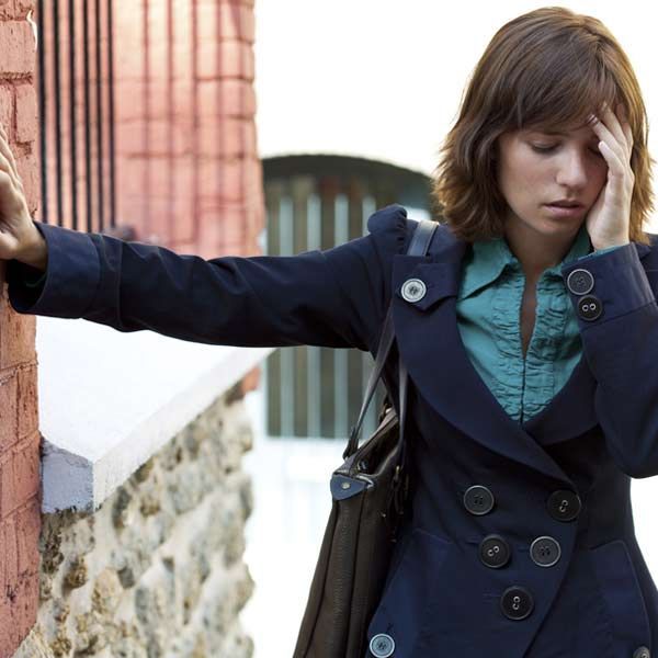 Balance and coordination Issues are common symptoms of Huntington's Disease A woman leaning against a brick wall, having trouble with coordination because of Huntington's Disease