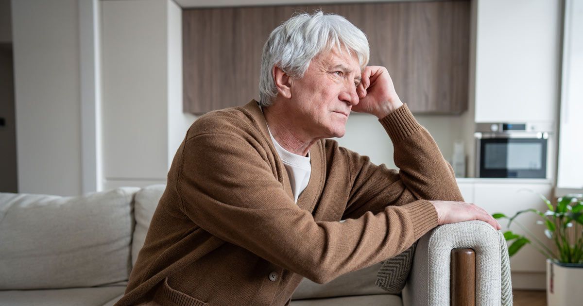 An older person with gray hair rests arm on the sofa with cognitive decline needing Huntingtons Disease treatments NYC