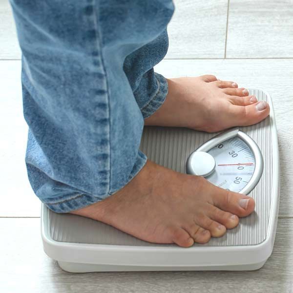 Rapid unhealthy weight loss is a symptom of Hyperthyroidism. A person is standing on a scale with their feet on it representing Hyperthyroidism Treatments