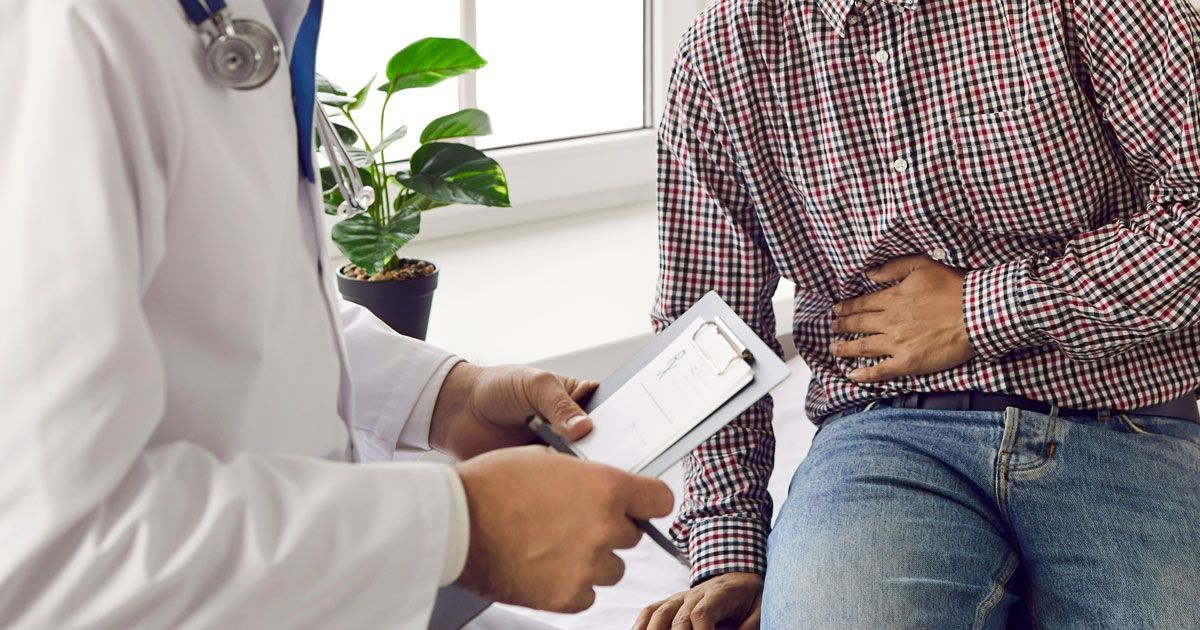 A doctor examining a seated patient with his hand on his abdomen, likely indicating stomach pain IBD Treatments NYC - Dr. John Salerno