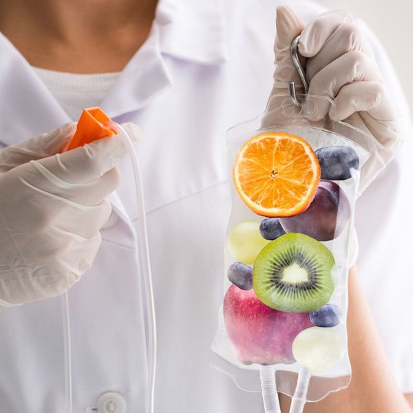 A nurse is holding an IV bag of fruit in her hand representing All Vitamins IV Treatments