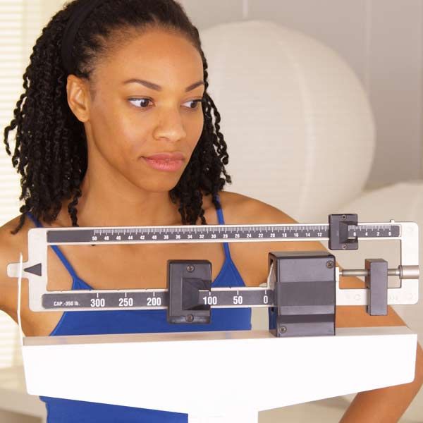 A person is looking at a medical balance scale unhappy with no weight loss progress.
