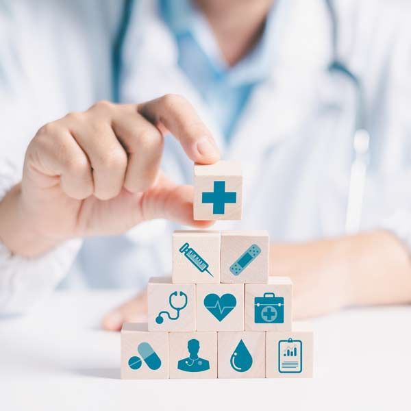 Integrative Medical Practitioner in Manhattan, NY and Connecticut building a pyramid of wooden blocks with medical icons representing