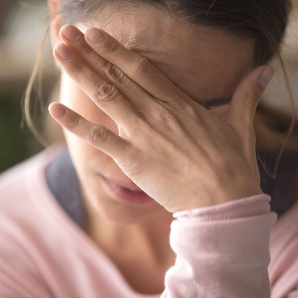 Woman with hand covering face, showing stressed fatigue from microplastics toxicity