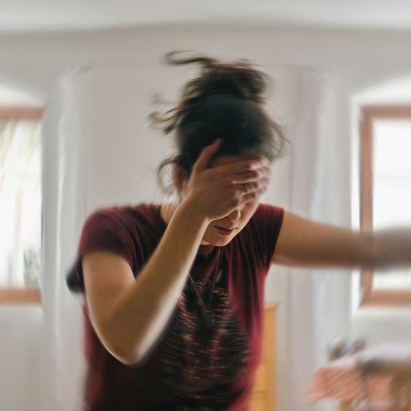 A woman in a red shirt is covering her face with her hand representing Migraine Treatments