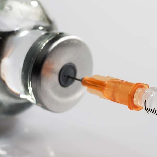 A syringe is being inserted into a bottle of liquid representing GLP-1 Therapy for Diabetes and Weight Loss