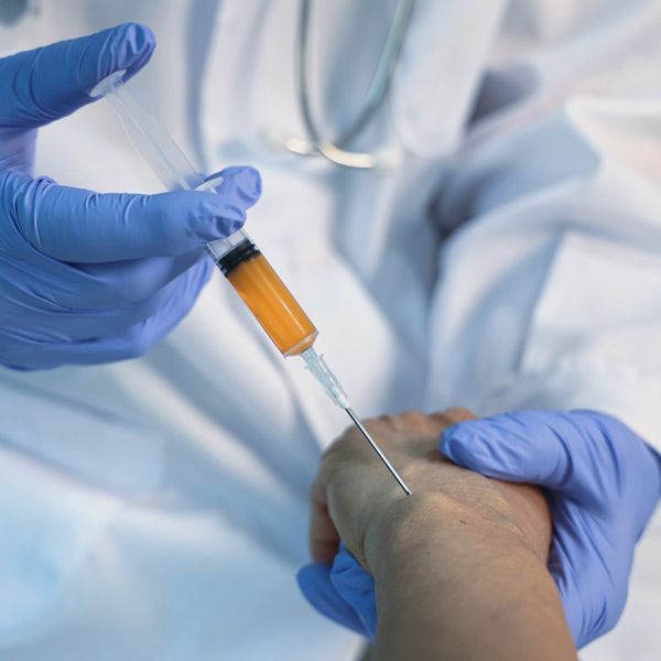 A person in blue gloves is getting an injection in their hand representing Platelet-Rich Plasma (PRP) Treatments