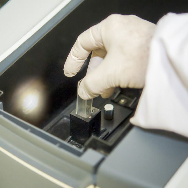 A person wearing white gloves is putting a test tube of blood into a machine representing Ultraviolet Blood Irradiation Treatments