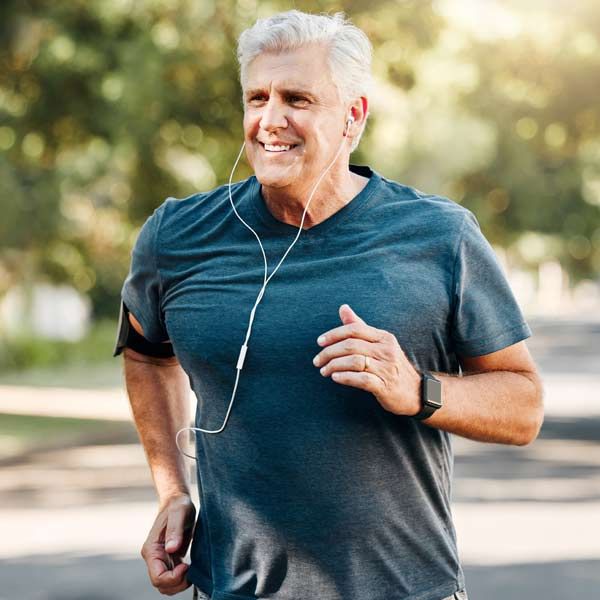 A man wearing headphones is running down a street thanks to his Myers Cocktail IV Treatments
