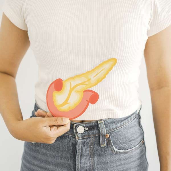 A woman is holding a drawing of a pancreas on her stomach indicating Pancreatitis Treatments