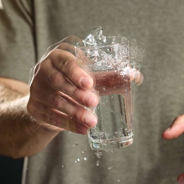 A person is holding a glass of water with water splashing out of it, representing Parkinson's Disease IV Treatments