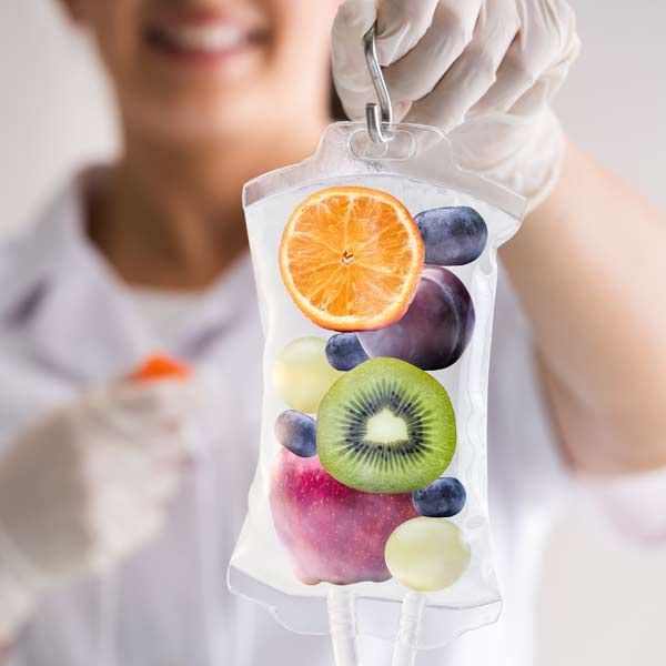 A woman is holding an IV bag of fruit in her hand. Representing Vitamin C IV Treatments