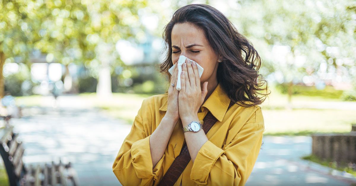 A woman in a yellow shirt is blowing her nose into a napkin. What You Dont Know About Allergy Season