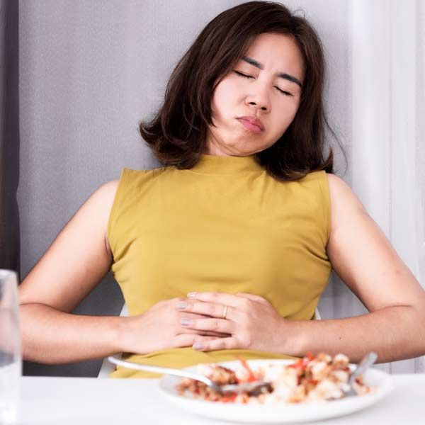 A woman is sitting at a table with a plate of food representing Zollinger-Ellison Syndrome Treatments