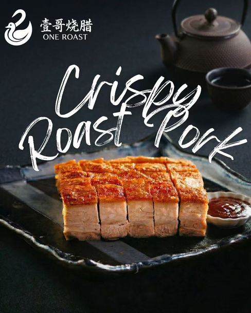 Crispy roast pork on a black plate with dipping sauce, shown as a food advertisement.