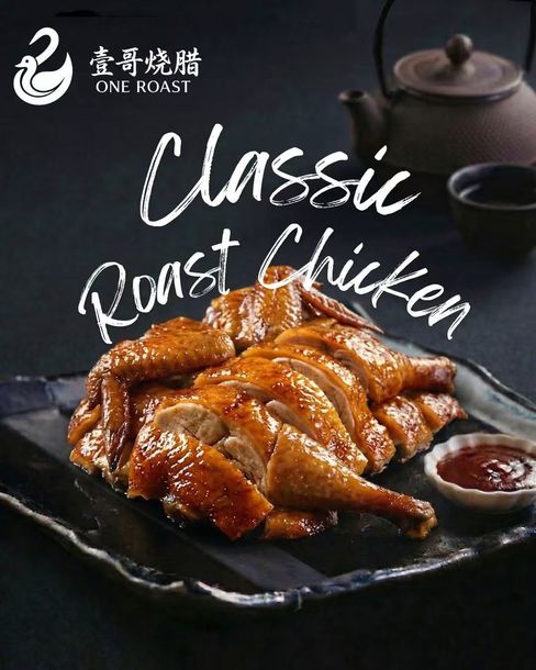 Classic roast chicken on a black plate with sauce, beside a teapot on a dark background.