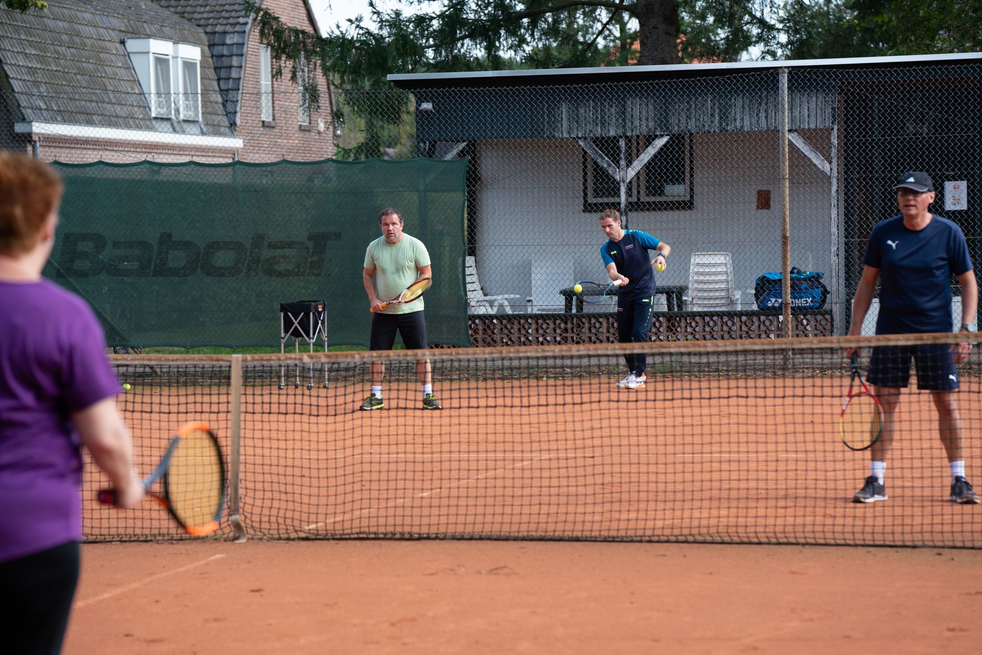 Een groep mensen speelt tennis op een tennisbaan.