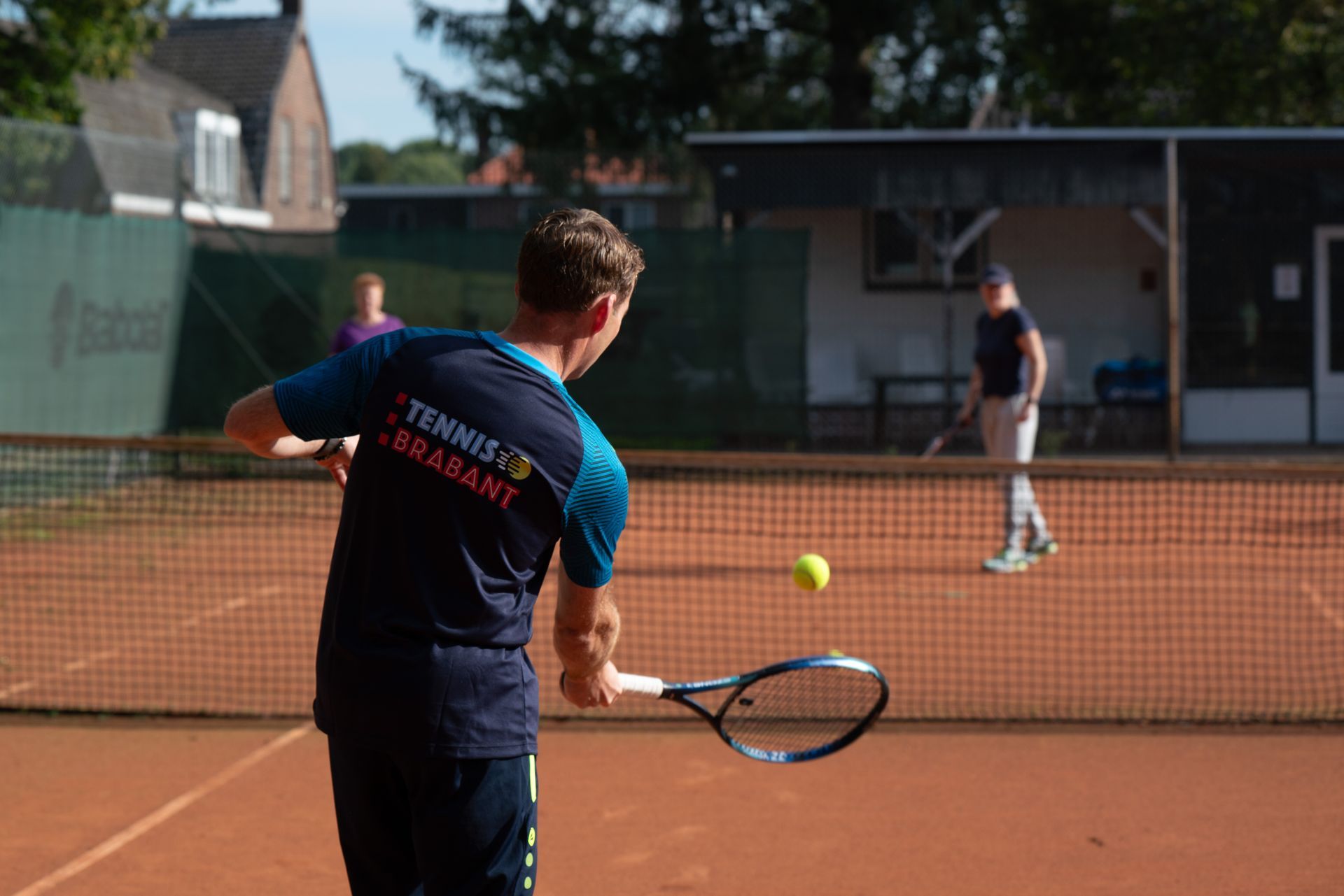 Een tennistrainer speelt tennis op een tennisbaan.