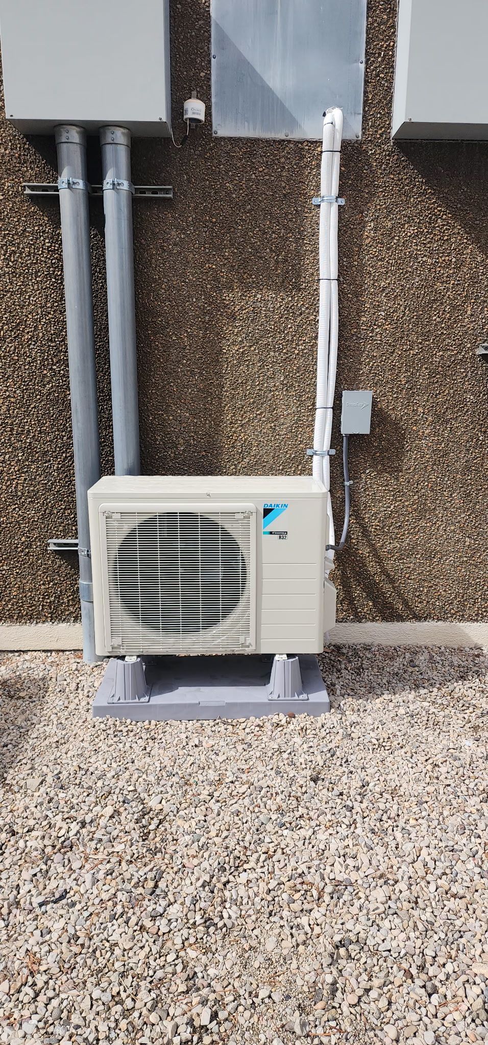 A white air conditioner is mounted on the side of a building.