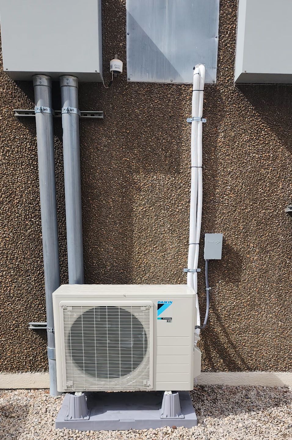 A white air conditioner is mounted on the side of a building.