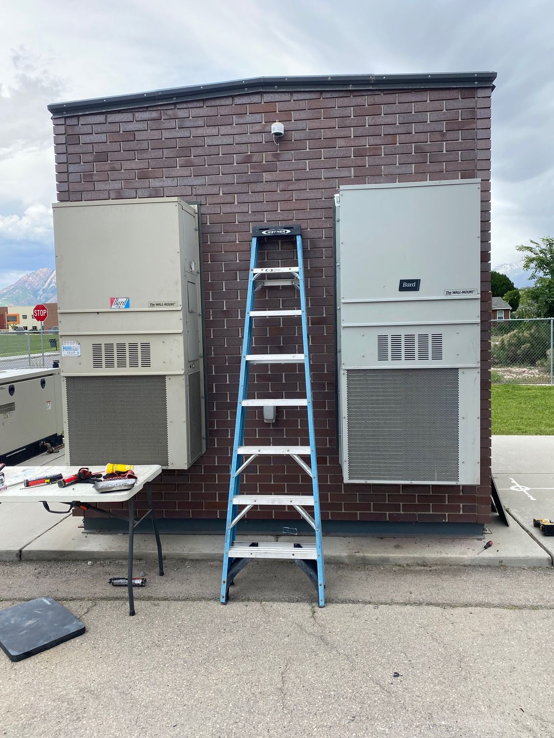 A ladder is leaning against a brick wall next to a table.