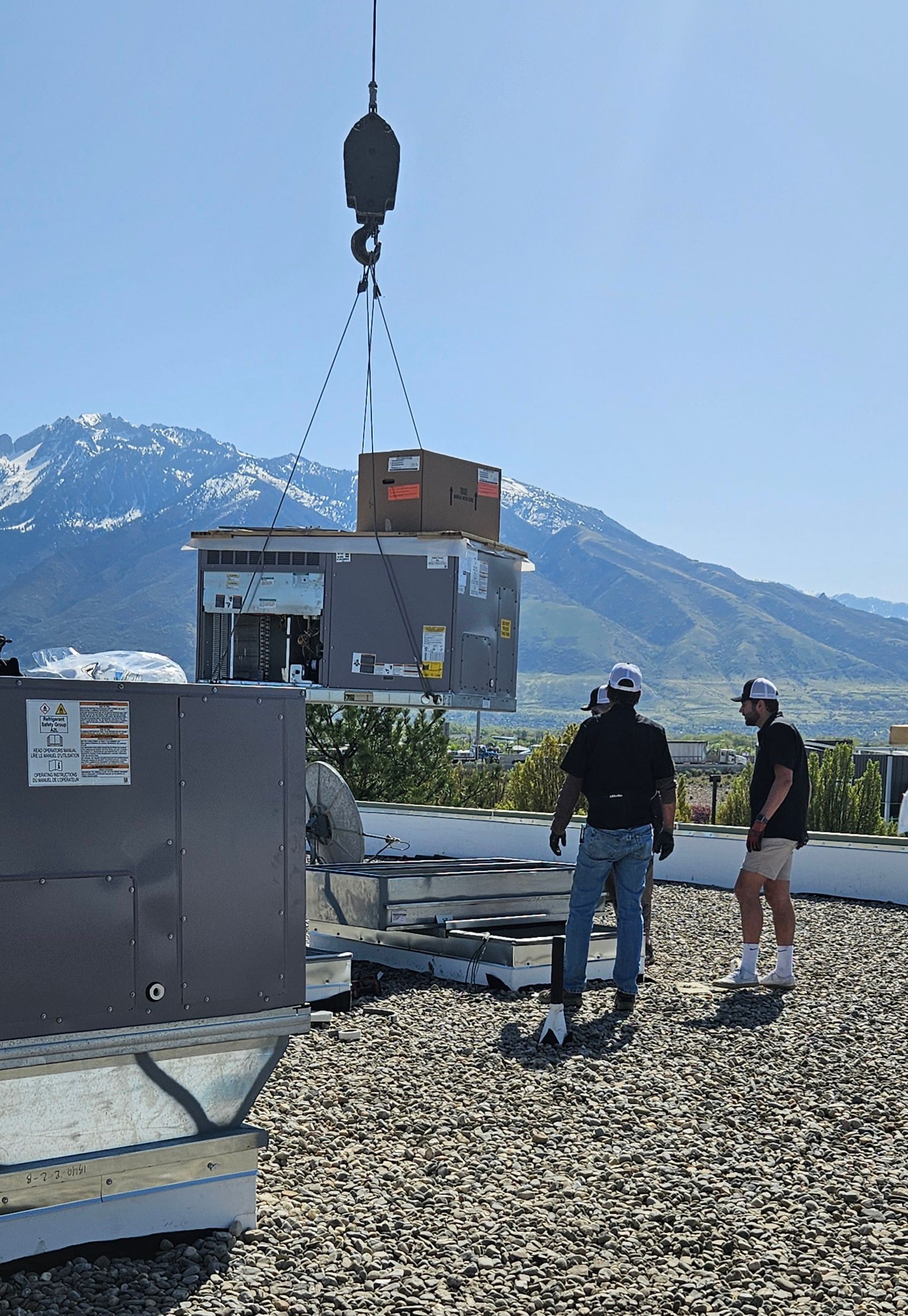 Two men are working on a roof with mountains in the background.