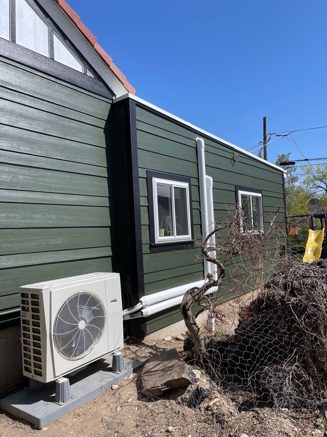 A green house with a white air conditioner on the side of it.