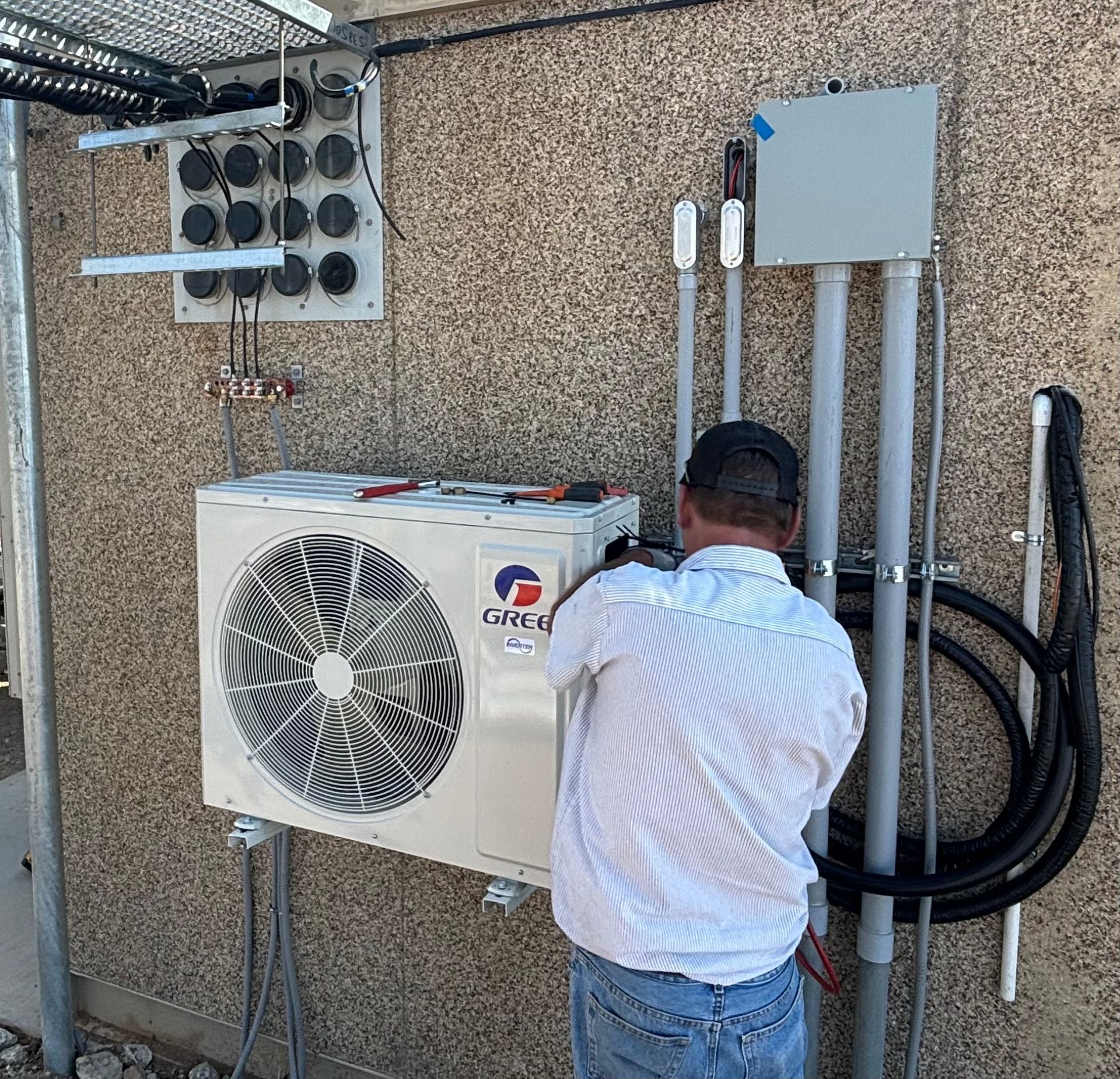 A man is working on an air conditioner on the side of a building.