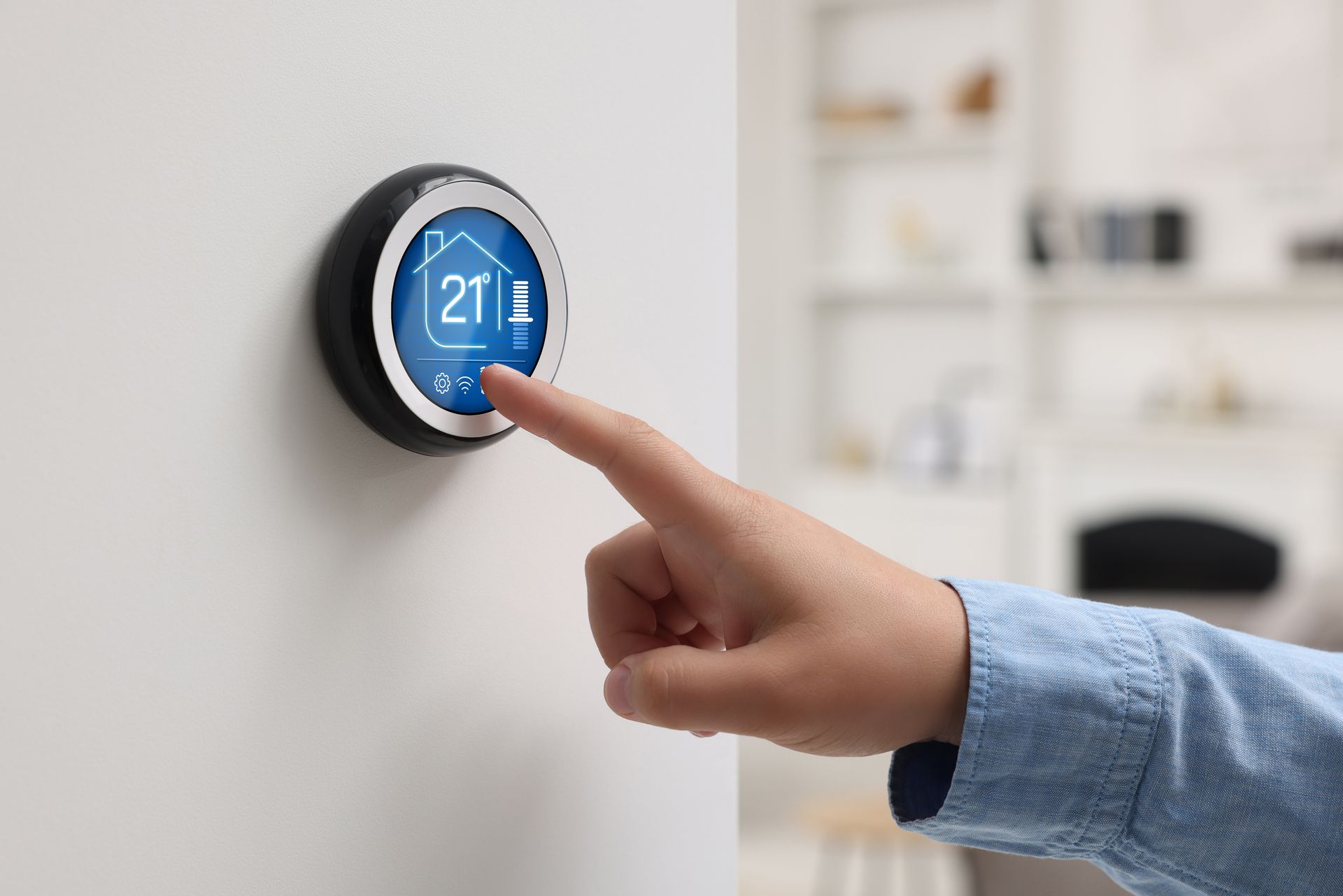 A person is pressing a button on a thermostat.