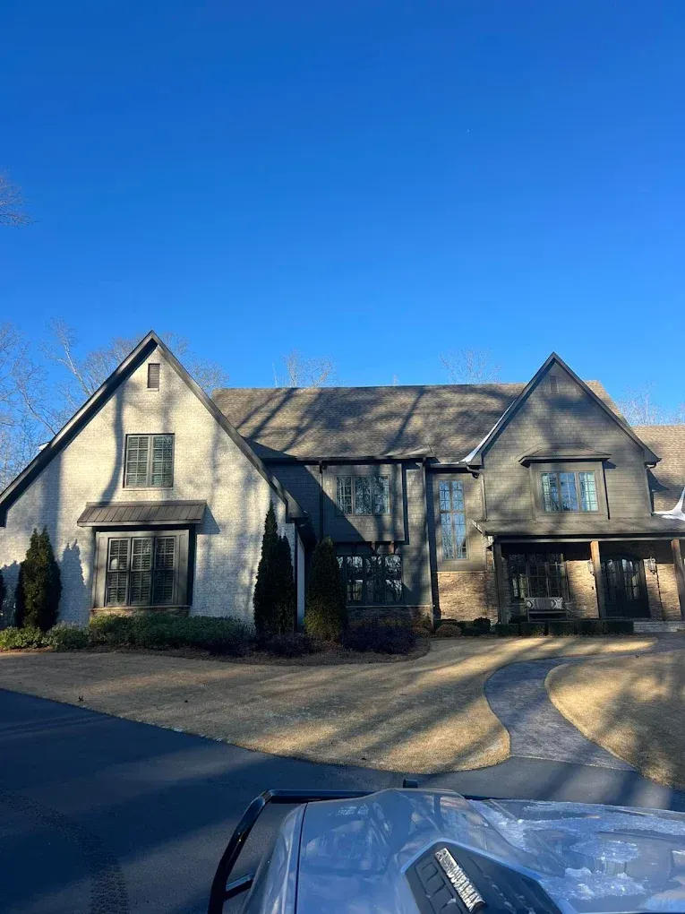 Large gray house with multiple gables and a dark roof under a clear blue sky.
