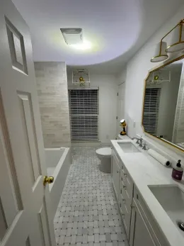 Bathroom with white cabinetry, marble countertops, tiled floor, and a large mirror.