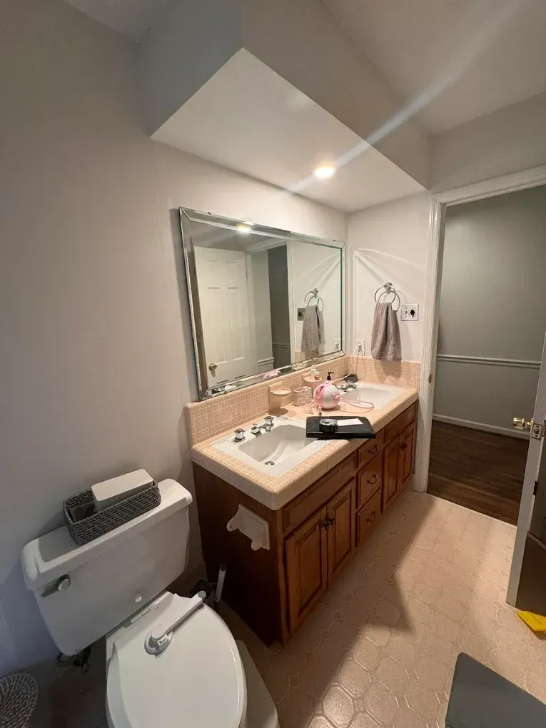 Bathroom with vanity, toilet, and doorway. Beige, brown, and white colors.