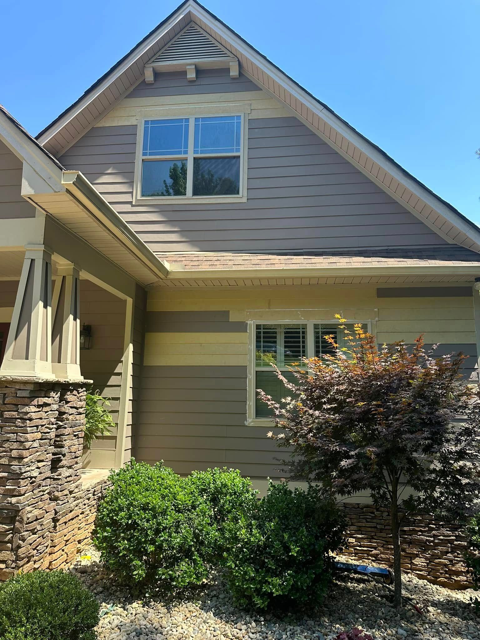 House exterior with stone, siding, and shrubs under a blue sky.