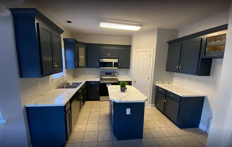 Navy blue kitchen cabinets with white countertops, island, and tile flooring.