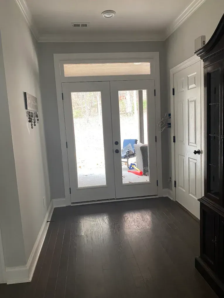 Hallway with dark wood floor, light gray walls, white trim, and double glass doors.