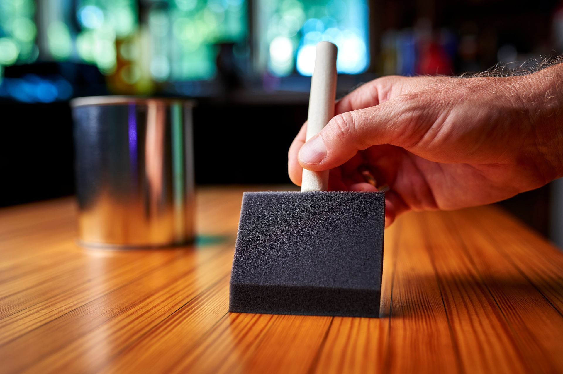 A person is using a sponge to paint a wooden table.
