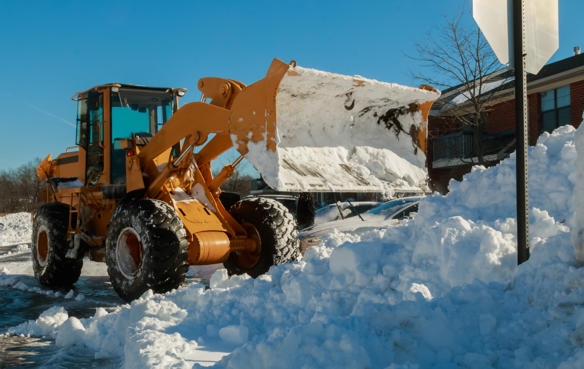 A bulldozer is clearing snow from a parking lot