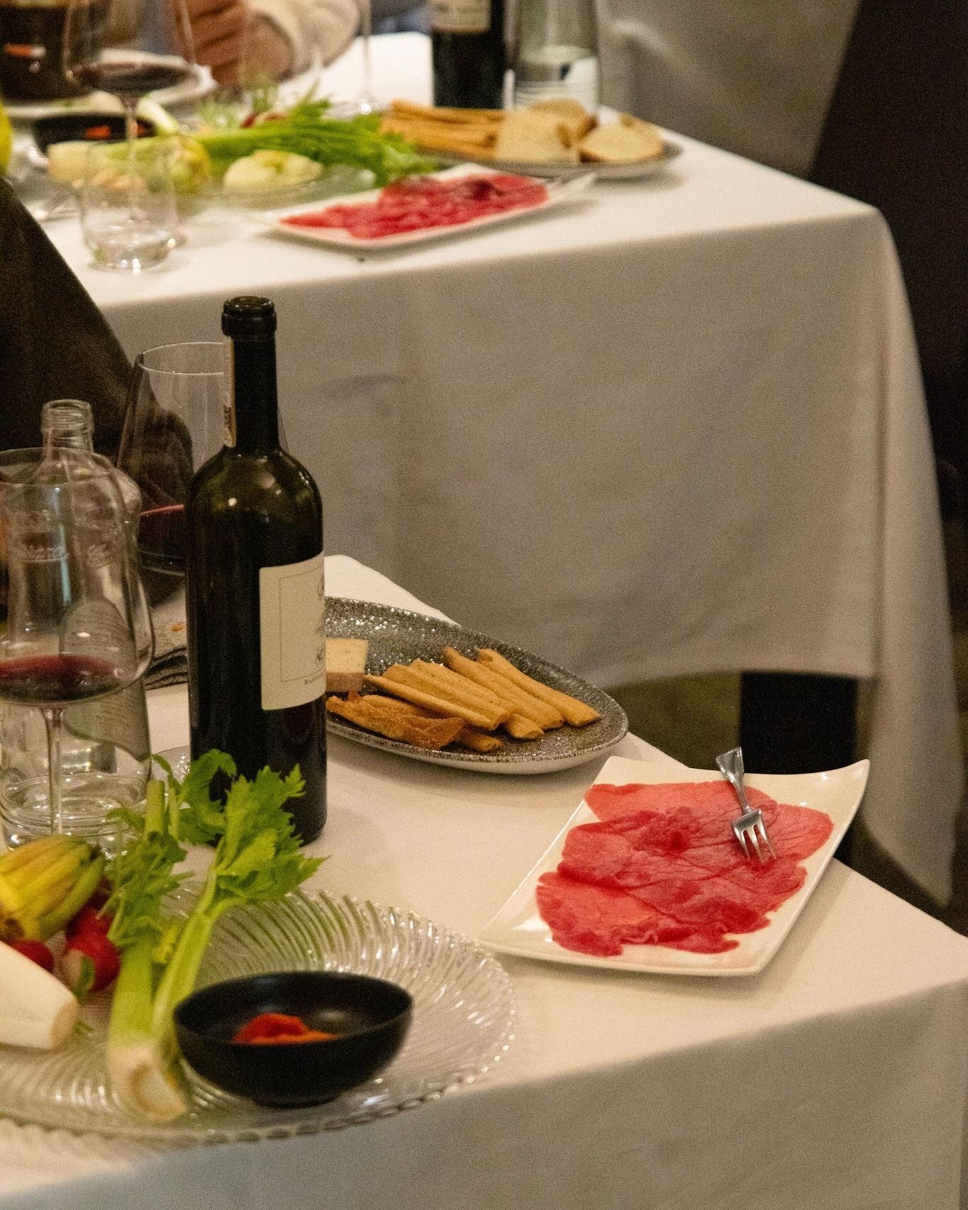 Un tavolo con piatti di cibo e una bottiglia di vino