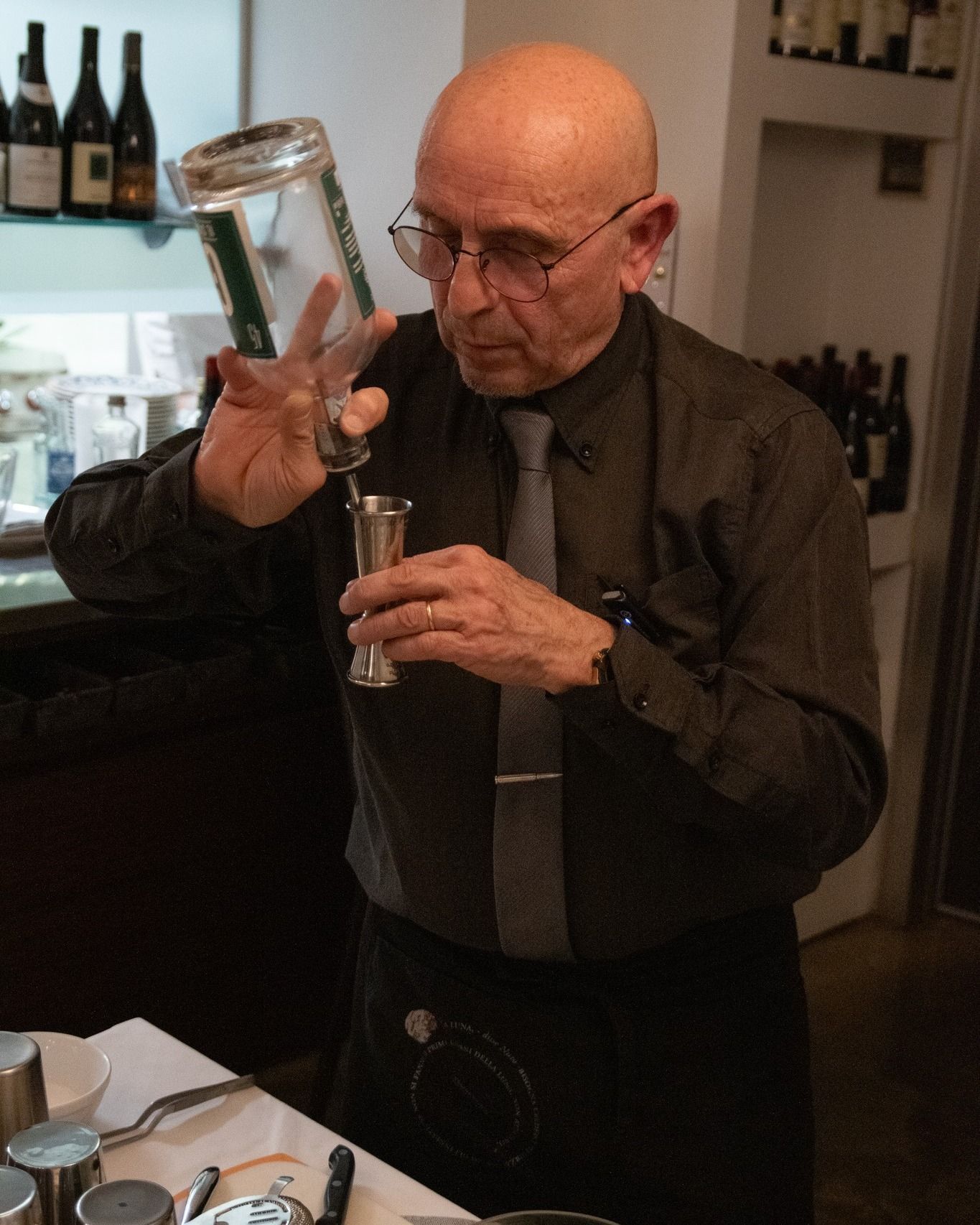 Un uomo in camicia nera e cravatta sta versando un drink in un bicchiere