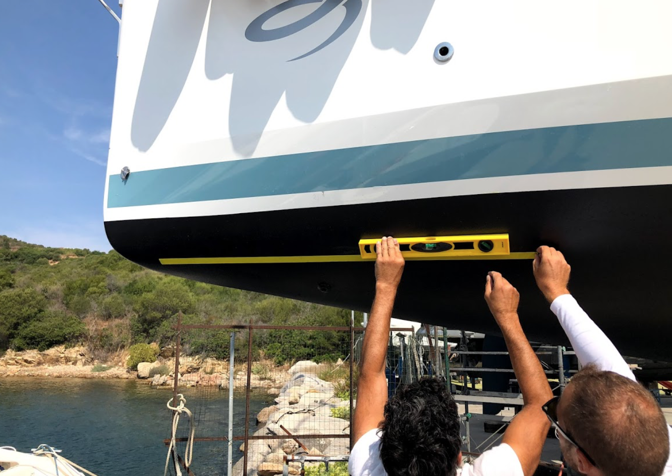 Two men are measuring a boat with a yellow level