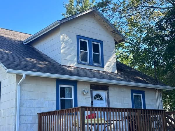 A white house with blue trim and a wooden deck