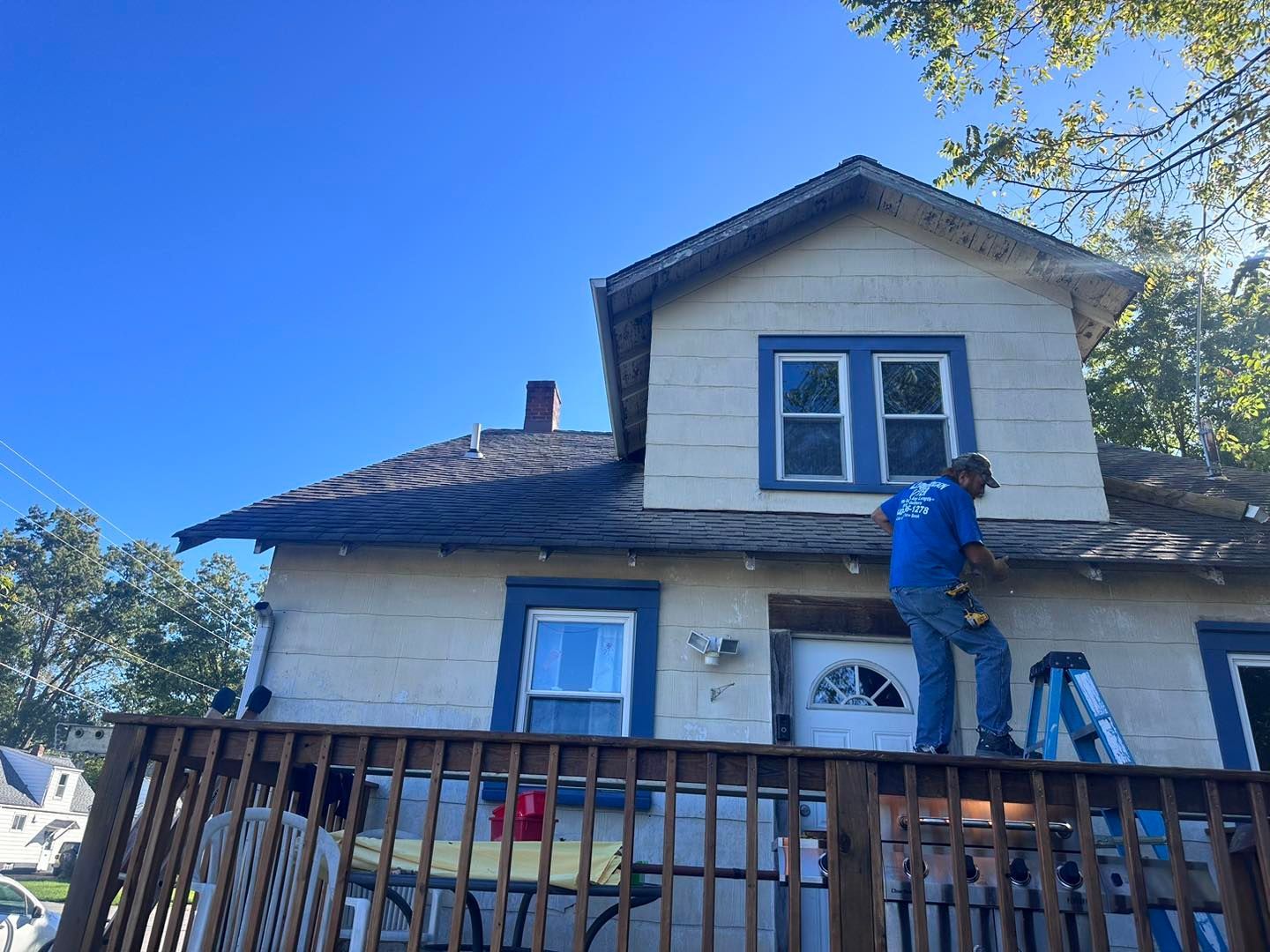 A man is standing on a ladder in front of a house.