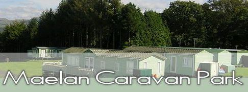 Photo of caravan park with green caravans and mountains in distance