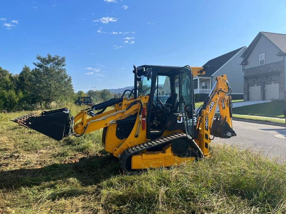 A yellow tractor is parked in a grassy field in front of a house.