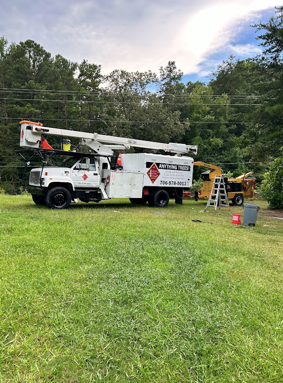 A white truck with a crane on top of it is parked in a grassy field.